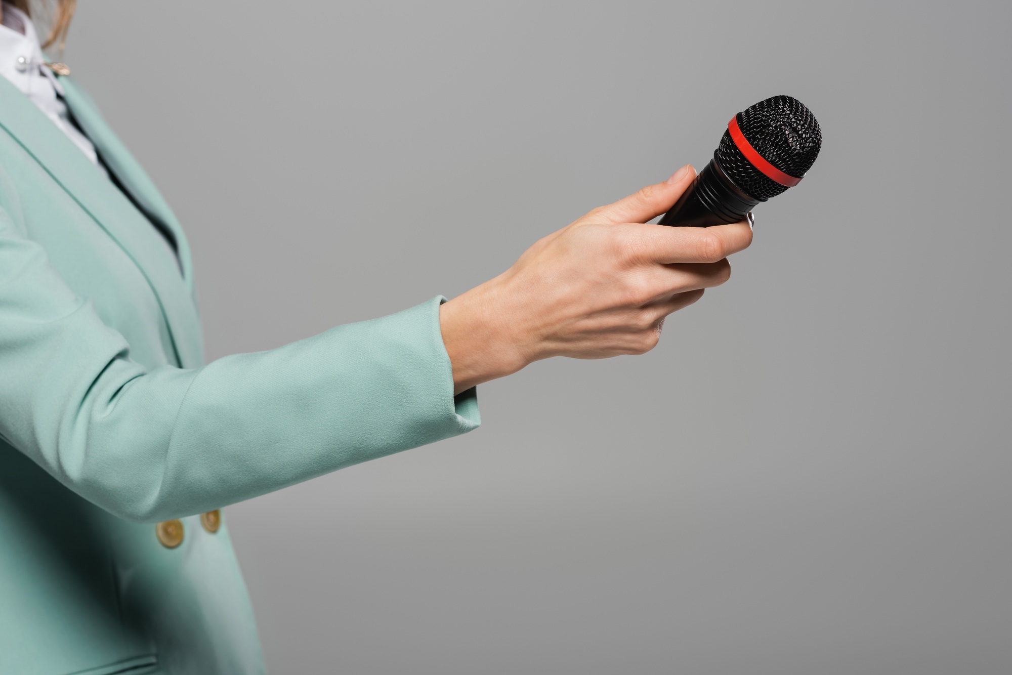 Cropped view of event host in green jacket holding wireless microphone during party and performance